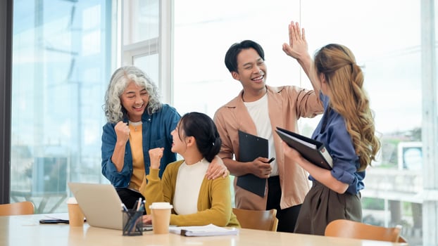 A group of businesspeople celebrates their project success in the office, giving high-fives. photo