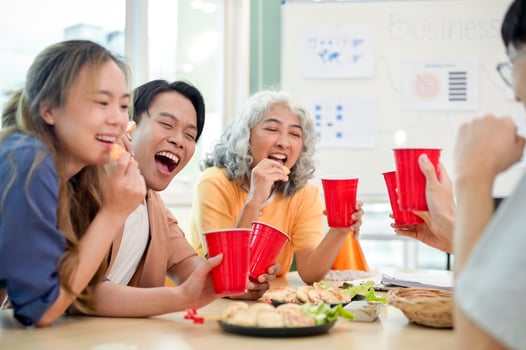 A group of joyful Asian startup businesspeople celebrate in the office, chatting, enjoying drinks. photo