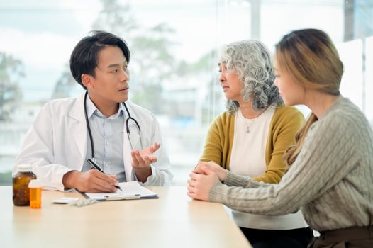 A professional Asian male doctor is discussing the treatment plan with a patient and her caregiver. photo