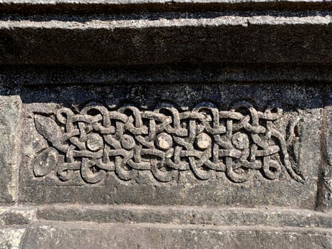 A detailed closeup of a snake carving on Halebidu Temples wall in Karnataka showcases Hoysala artistry, with precise scales, coiled form, and intricate light and shadow details. photo