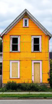 A yellow house with boarded up windows photo