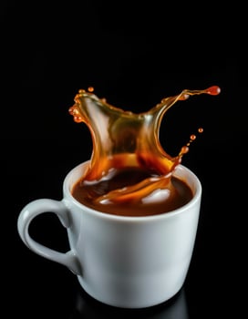 Coffee splash captured in a white cup against a black background highlighting the motion and freshness of the beverage photo