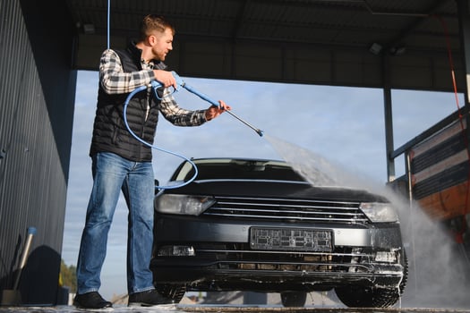 Car wash. Man washes car with water from high pressure washer photo