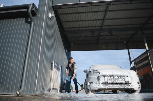 Car wash equipment. A man is washing a car at self service car wash. High pressure vehicle washer machine sprays foam photo