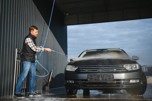 Car wash. Man washes car with water from high pressure washer photo