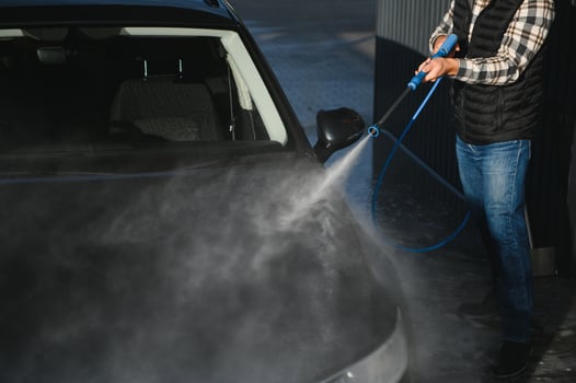 Car wash. Man washes car with water from high pressure washer photo