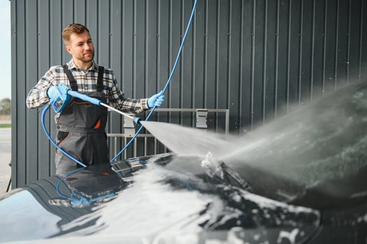 Man worker washing car service. Car wash cleaning station high pressure water. Employees clean a vehicle professionally photo