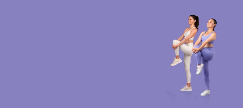Two women in stylish activewear are performing fitness exercises on a soft purple background. Their posture emphasizes strength and energy, showcasing a commitment to health and fitness. photo