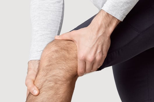 Athlete has knee pain, man presses hands to leg, cropped photo
