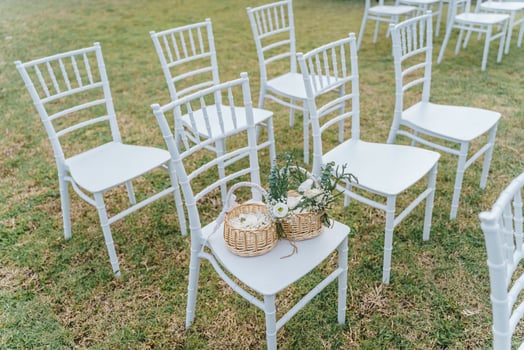 Setup white chairs on grass at wedding with wedding flowers in basket. Garden wedding photo