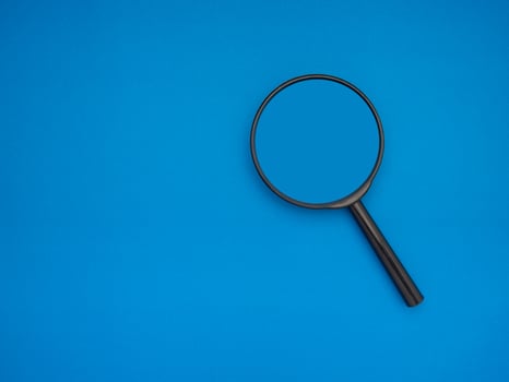 Search concept. A magnifying glass on a blue background with copy space for text photo
