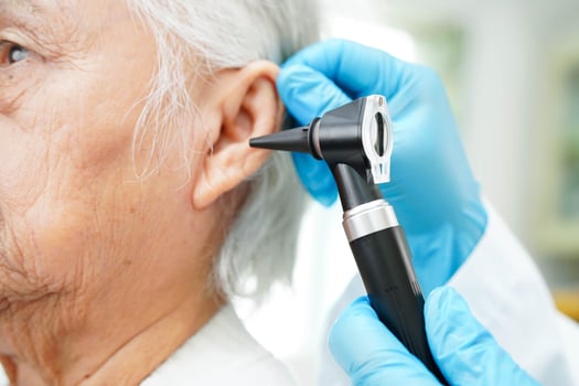 Otolaryngologist or ENT physician doctor examining senior patient ear with otoscope, hearing loss problem. photo