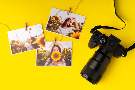 Photo camera with colorful printer photos on yellow background