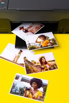 Printer printing colorful photos of people close up, yellow background