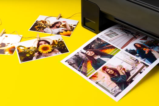 Printer printing colorful photos of people close up, yellow background