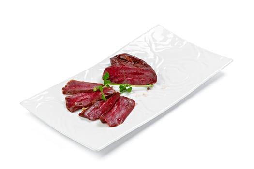 Thin pieces of sliced sausage on white plate isolated on white photo