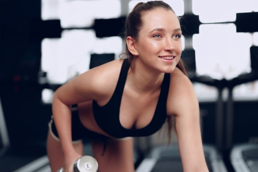 Young brunette sporty woman exercising with dumbbell in a gym photo