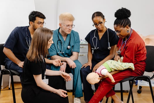 Group of doctors sitting together with baby mannequin at first aid training course photo
