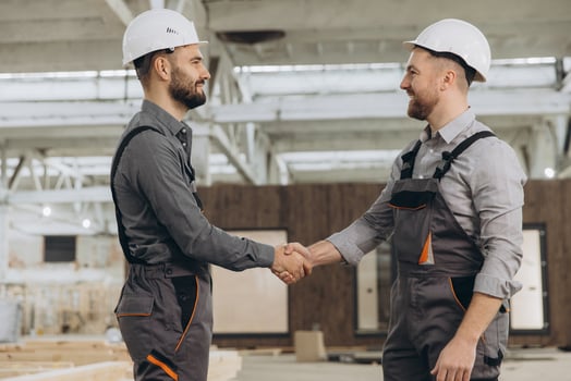 Construction workers shaking hands at modular building factory photo