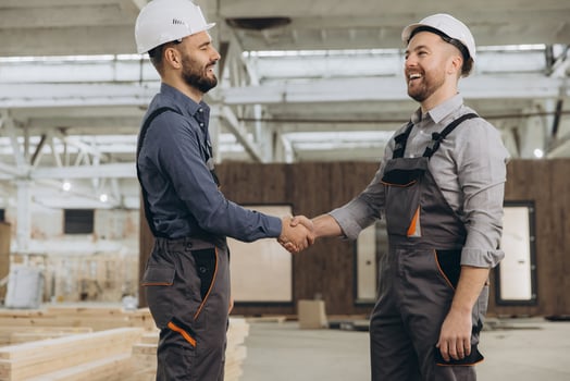 Construction workers shaking hands at modular building factory photo