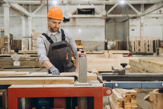 Carpenter cutting wooden plank using saw in workshop for modular building photo