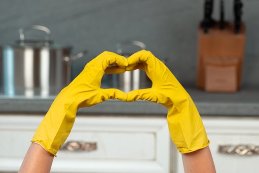 Hands in yellow gloves against kitchen background. Housekeeping concept photo