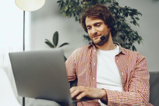 Young man wearing headset doing a call by laptop photo