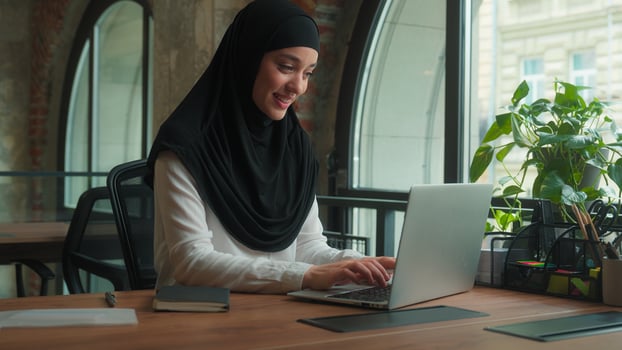 Muslim woman in hijab female worker freelancer student Arabian businesswoman employee office manager agent online laptop remote work at workplace using computer pc smiling islamic girl business lady photo