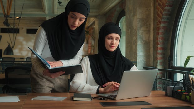 Arabian muslim islamic women in hijab arabic girls ladies business partners colleagues female businesswomen discussing online project computer tech intern talk advice teamwork working laptop at office photo