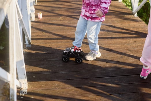 A playful child joyfully maneuvering a remotecontrolled truck while standing on a bridge photo