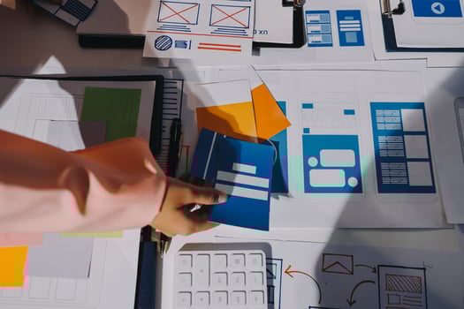 A person is working on a computer with a bunch of papers photo