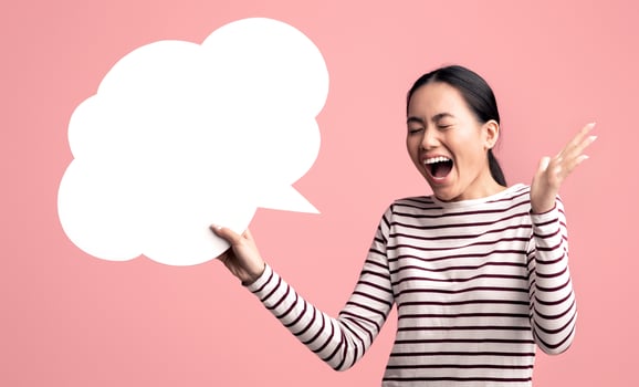 Happy Surprised Asian Woman Holding Blank Speech Bubble And Exclaiming With Excitement, Cheerful Young Korean Lady Emotionally Reacting To Nice Offer While Standing On Pink Background, Copy Space photo
