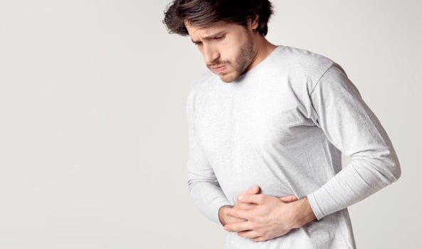 Young man hands on stomach, having bad aches pain. Food poisoning, influenza, cramps photo