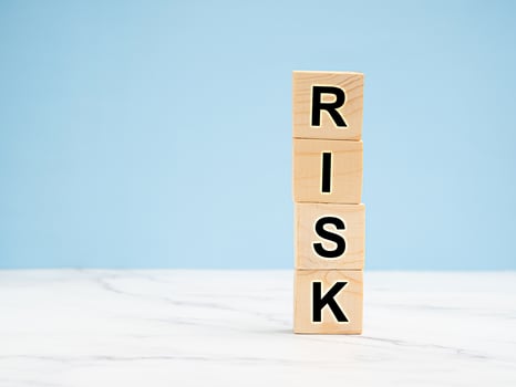 Wooden cubes with the letters RISK on a light blue background photo