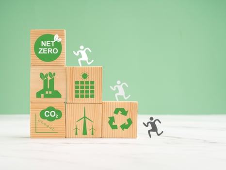 Net-zero emissions in 2050. World Earth day concept. Wooden cubes with eco-friendly icons over a marble floor against a green background photo