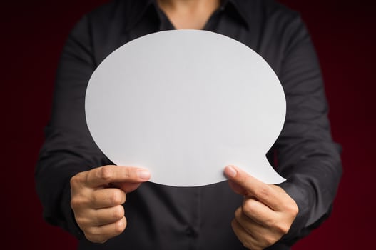 Text speech bubble concept. Close-up of hand holding a white speech bubble against a red background photo