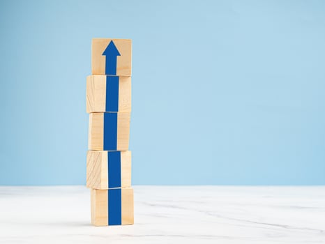 Common goal success concept. Arrow up on wooden cubes with a blue background photo
