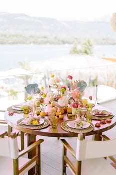 White chairs stand around a festive table with bright bouquets of flowers on the restaurant terrace photo