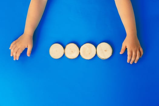 Hands of a kid with four wooden blocks, top view photo
