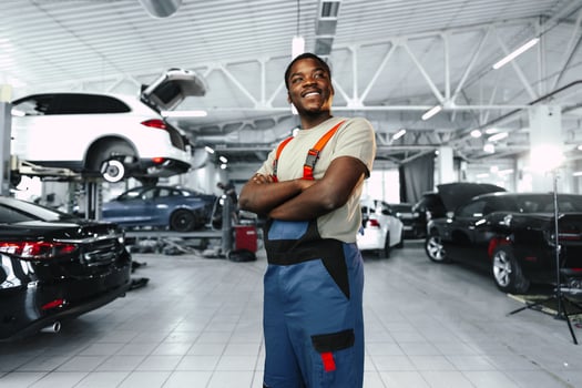 African man mechanic in uniform at the car repair station, portrait photo