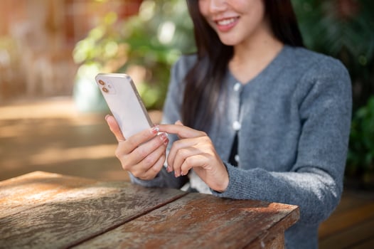 A woman sitting at an outdoor cafe table, using her smartphone to scroll through social media. photo