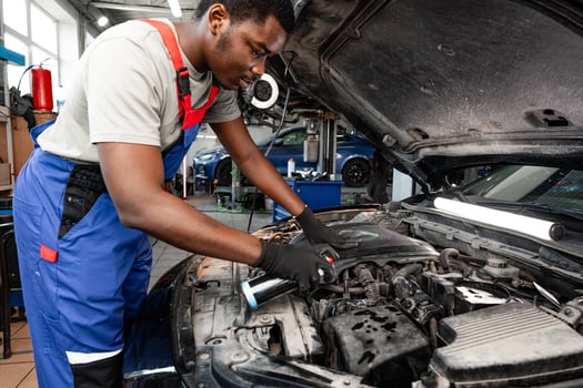 Young African male mechanic repairs car in garage close up photo