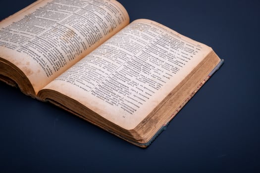 Close-up of an open antique dictionary against dark background. Selective focus photo
