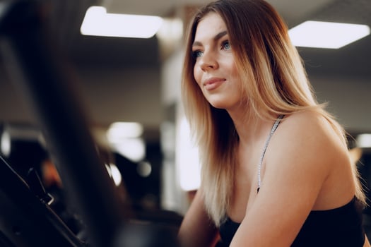 Fit curvy young blonde woman training in a cardio zone in a gym photo