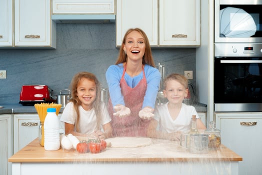 Young blonde woman, mother and her kids having fun while cooking dough photo