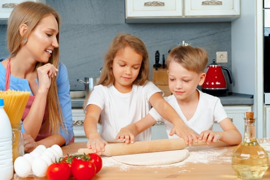Mother and her little kids, boy and girl, helping her to prepare dough photo