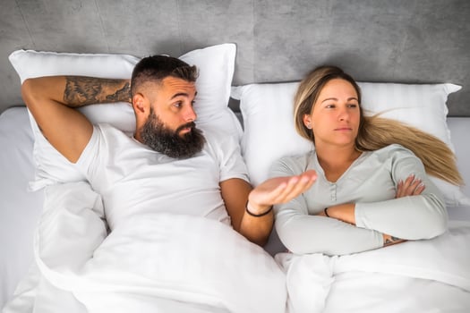 Couple is lying in bed and arguing. The woman is angry and offended and man is talking. photo