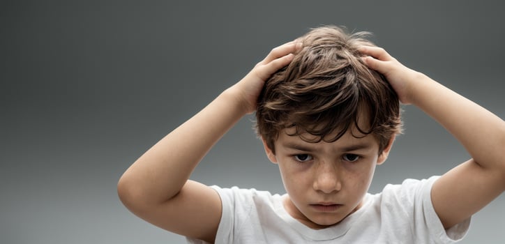 A young boy is holding his head in his hands photo