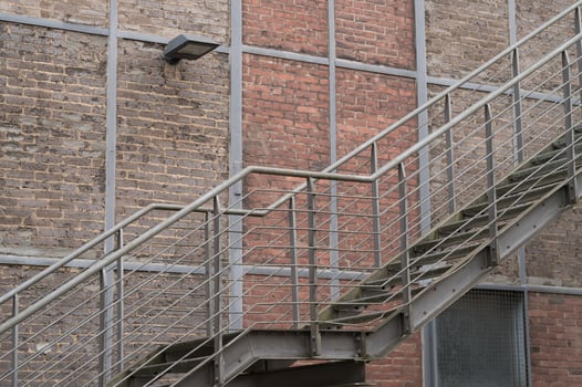 Metal staircase climbing a brick wall with lamp photo