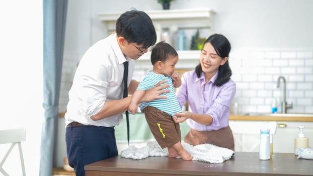 A man and woman are helping a baby on a table photo